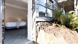 Quarto com cama, janela e parede de pedra visível.