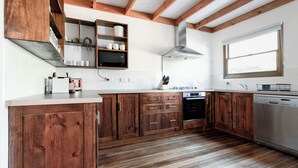 Uma cozinha com armários de madeira, lava-louças de aço inoxidável e janela com persianas.