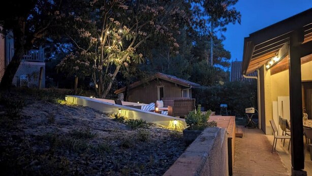 A modern outdoor seating area with a wooden deck and a small building in the background.