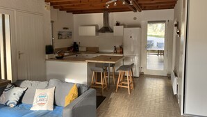A compact kitchen with a central island, wooden ceiling beams, and a view to the outside.