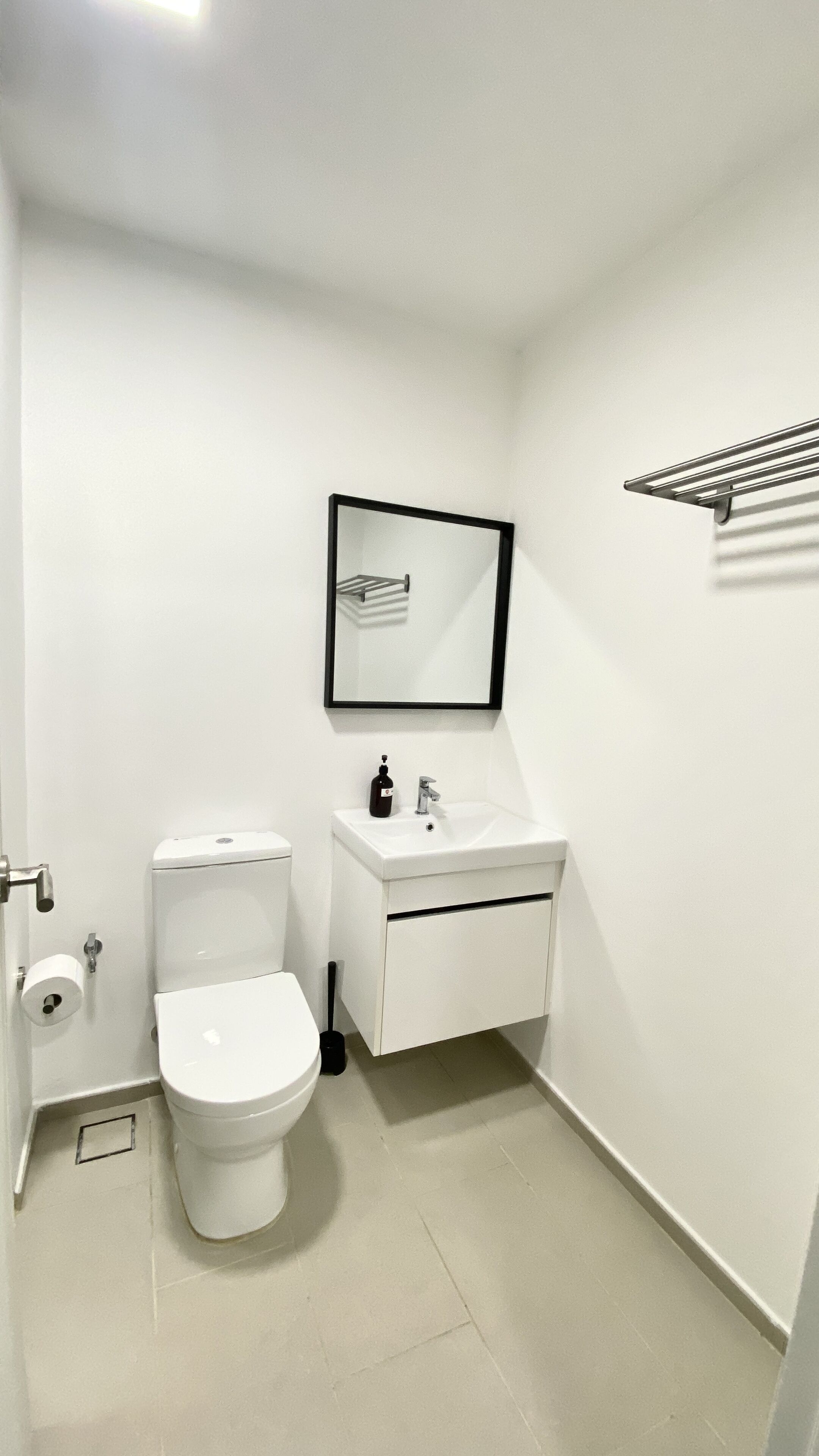 Une petite salle de bain blanche, avec des toilettes, un lavabo et un miroir.