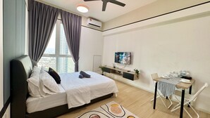 A modern bedroom with a bed, a desk, and a TV.
