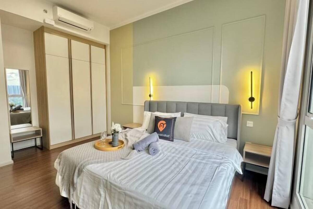 A modern hotel room with a large bed, bedside tables, an air conditioning unit, and a view of the outdoors.