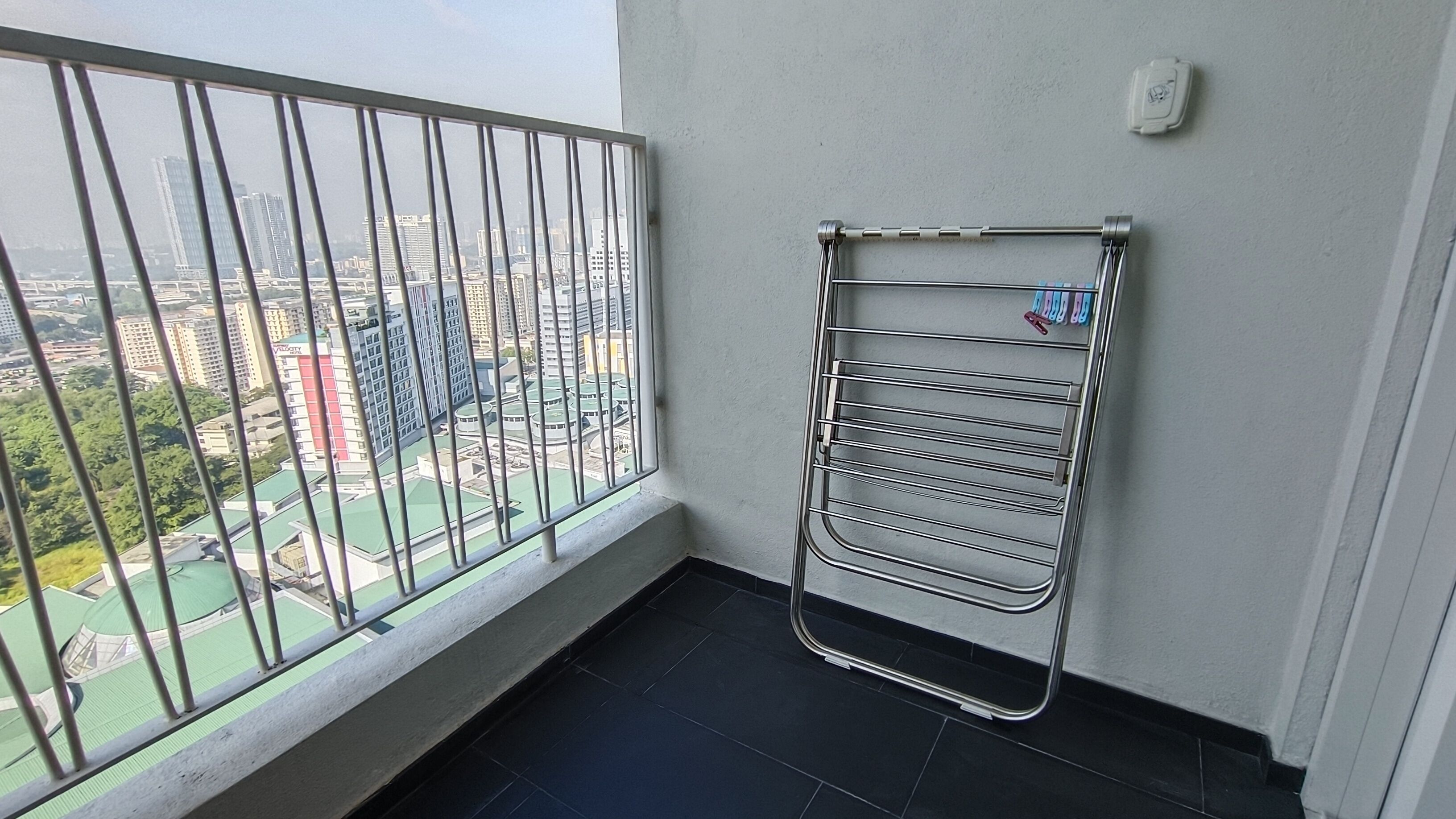 Een balkon met een metalen droogrek en uitzicht op een stadsgezicht.
