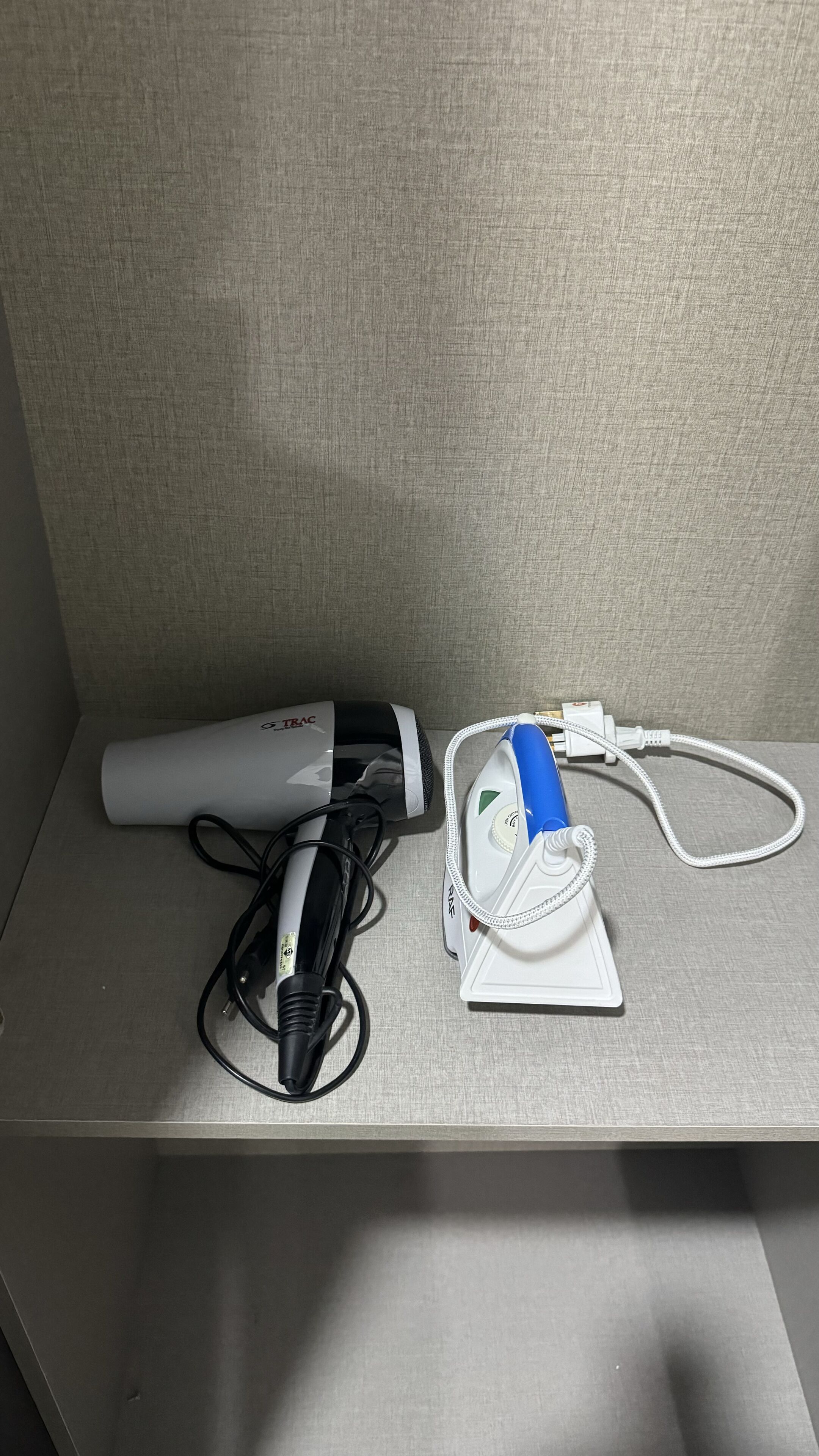 A desk with a hairdryer, a power strip, and a white device with a blue handle.