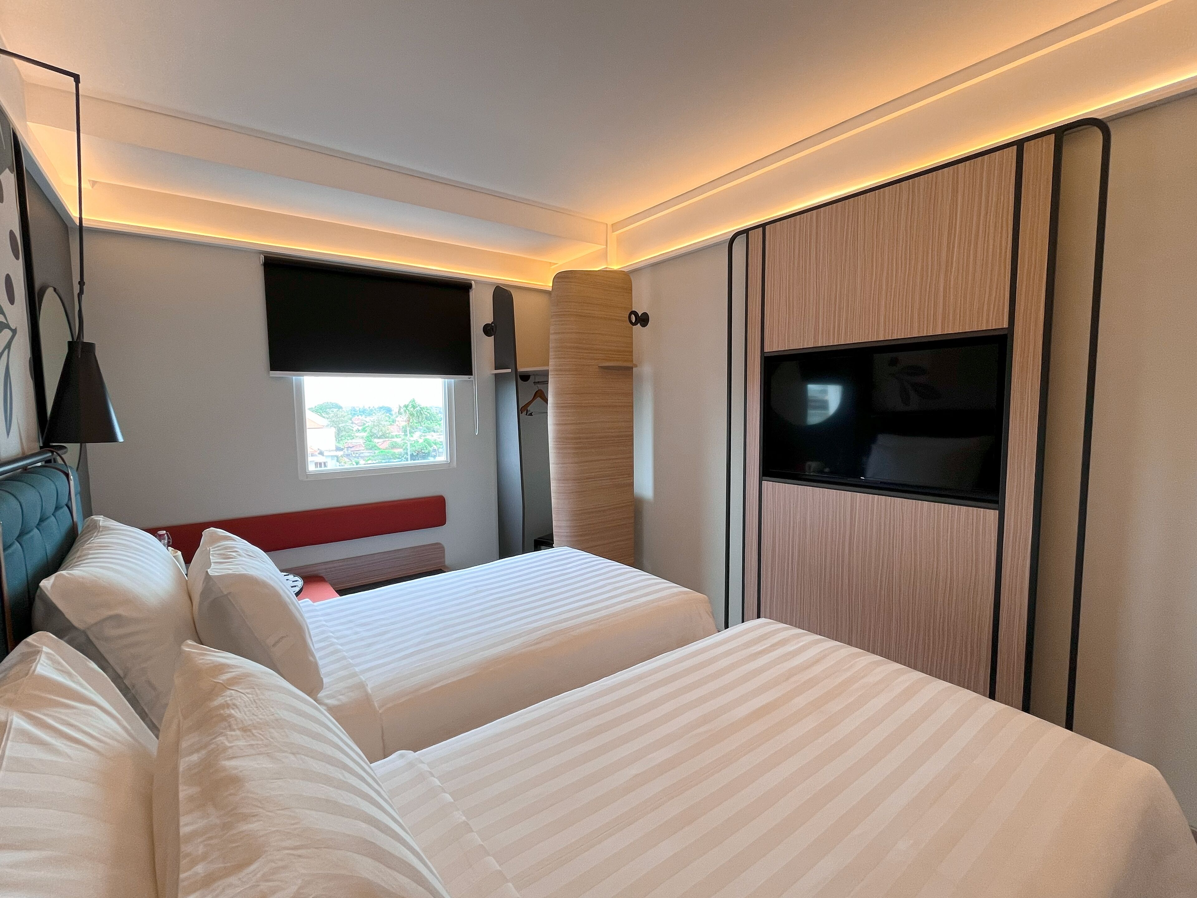 A hotel room with two beds, a TV, a window, and a wardrobe.