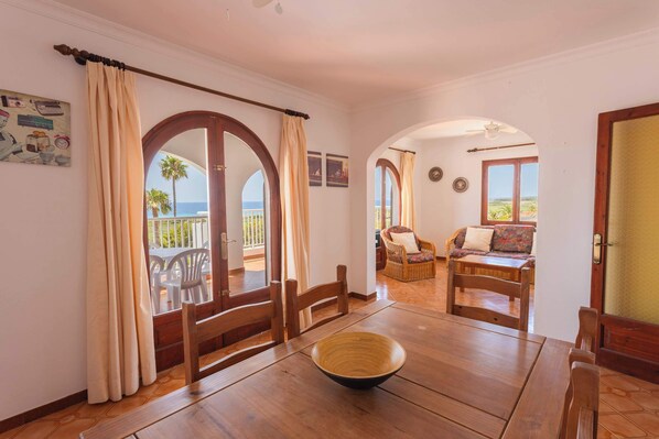 A room with wooden furniture, a large window with curtains, and a view of the outdoors.