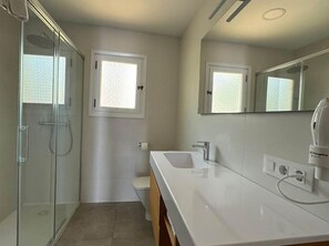 Ein Badezimmer mit Duschkabine, Toilette, Waschbecken und Spiegel.