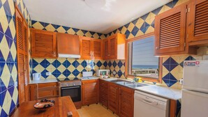 A kitchen with wooden cabinets, a white refrigerator, and a window with a view. - Villa Bautista - Beautiful Sea View (San Jaime Mediterráneo)