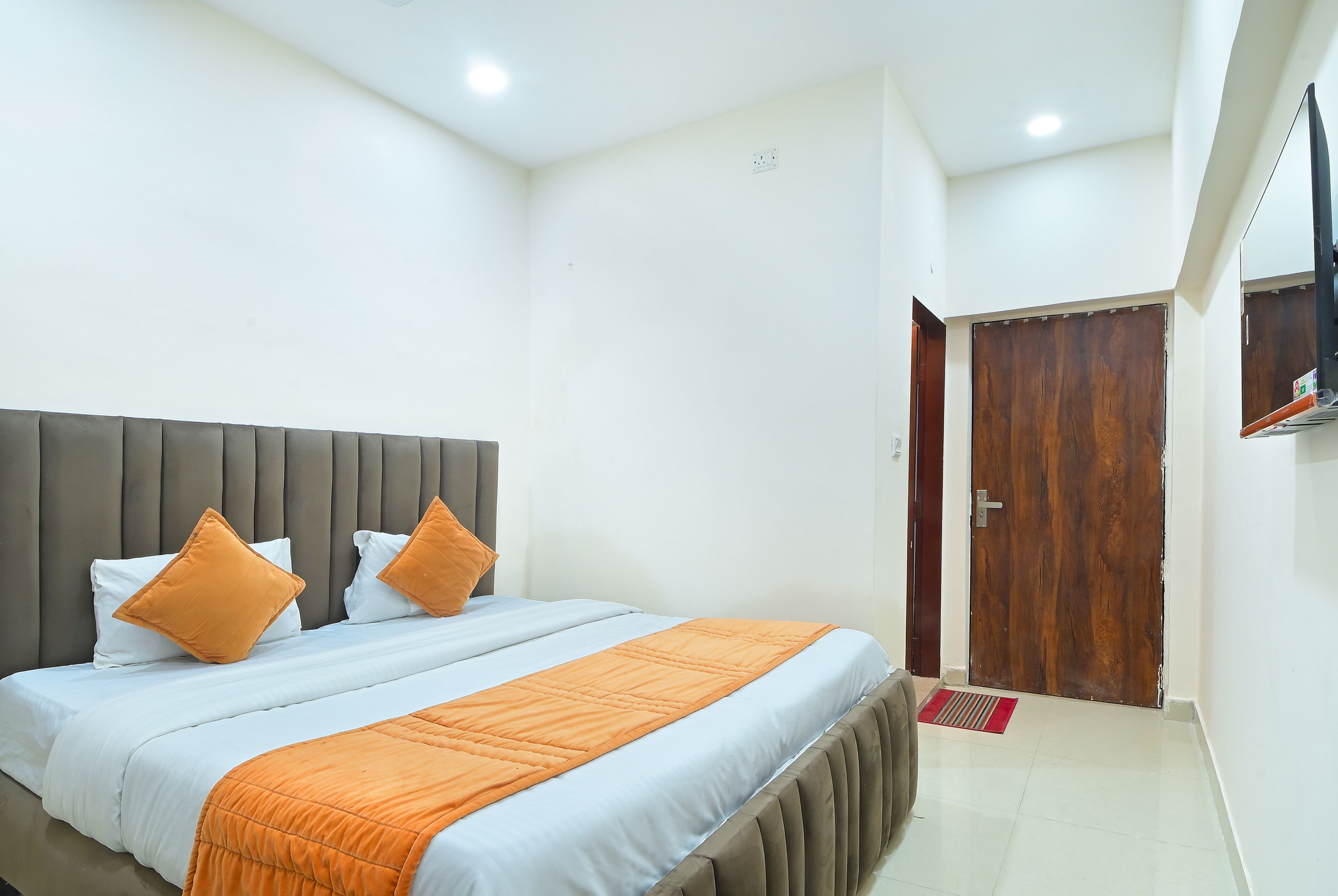 A bedroom with a bed, a wooden door, and a mirror on the wall.