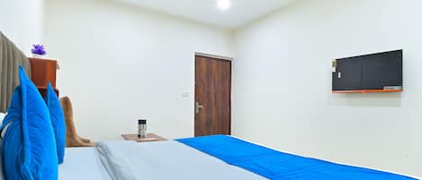 Una camera da letto con un letto, un armadio in legno, un comodino con una lampada, una ventola a soffitto e una TV a parete.