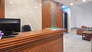 A reception desk with a television, a chair, and a potted plant. - Chowdhry Tourist Lodge- Paharganj-NDLS (New Delhi)