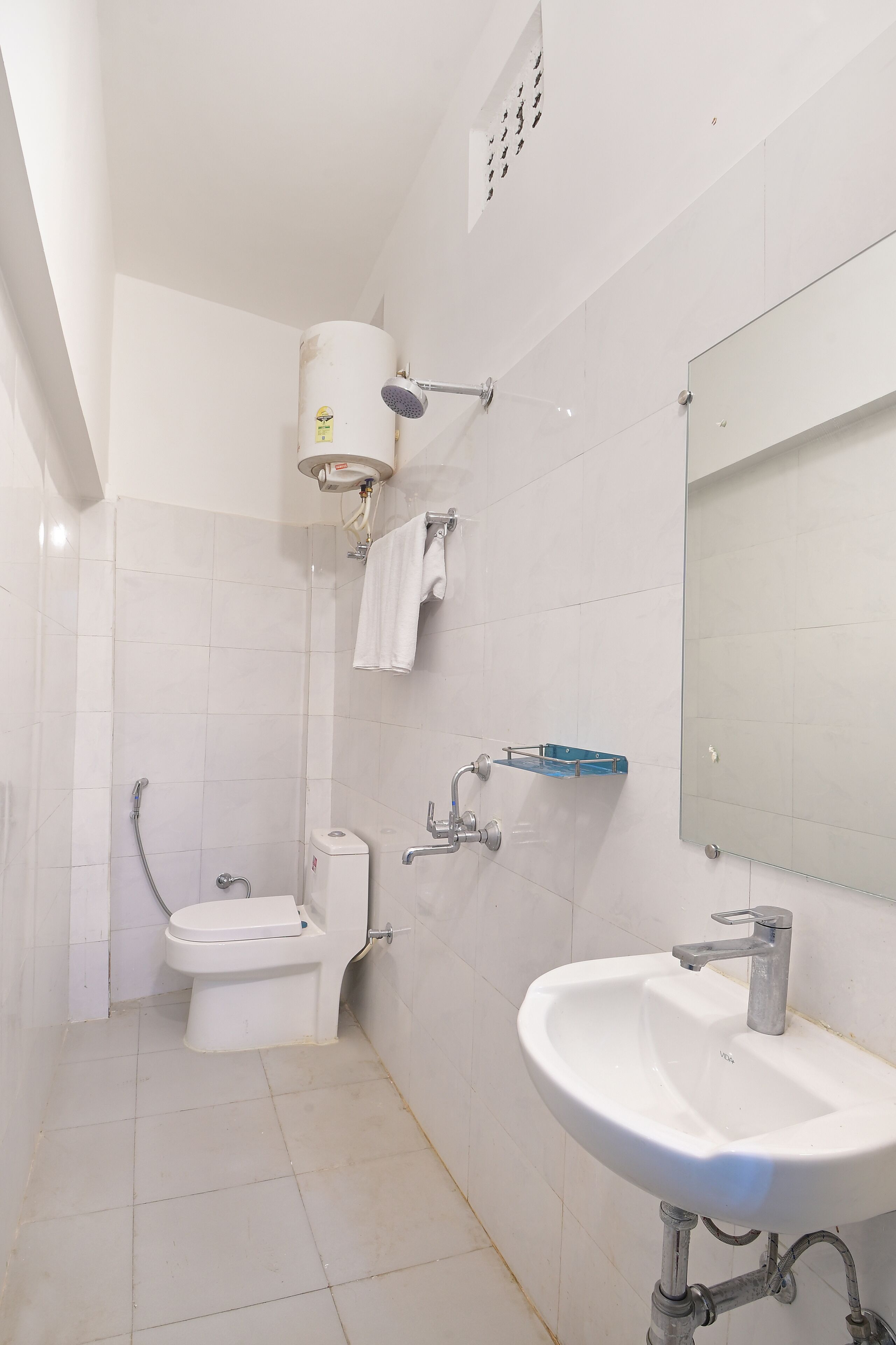 A modern bathroom with a toilet, bidet, sink, and a large mirror.