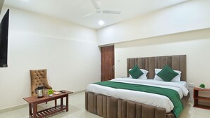 A bedroom with a bed, a chair, a table, and a ceiling fan. - Chowdhry Tourist Lodge- Paharganj-NDLS (New Delhi)