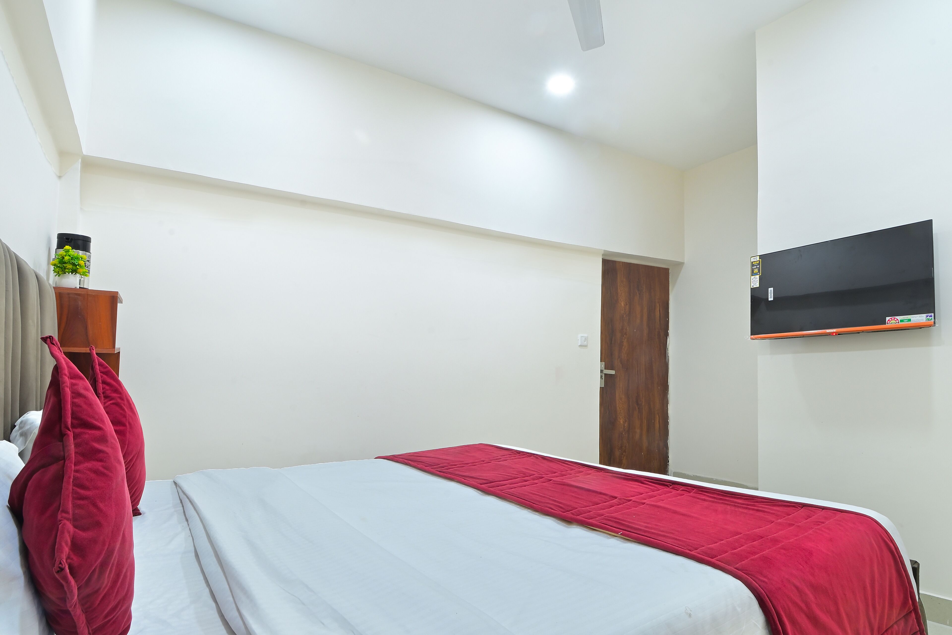 Una habitación de hotel con una cama, un televisor montado en la pared y una puerta que da a otra habitación.