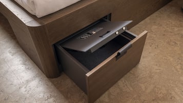 A wooden bed with a white mattress and a drawer with a control panel.