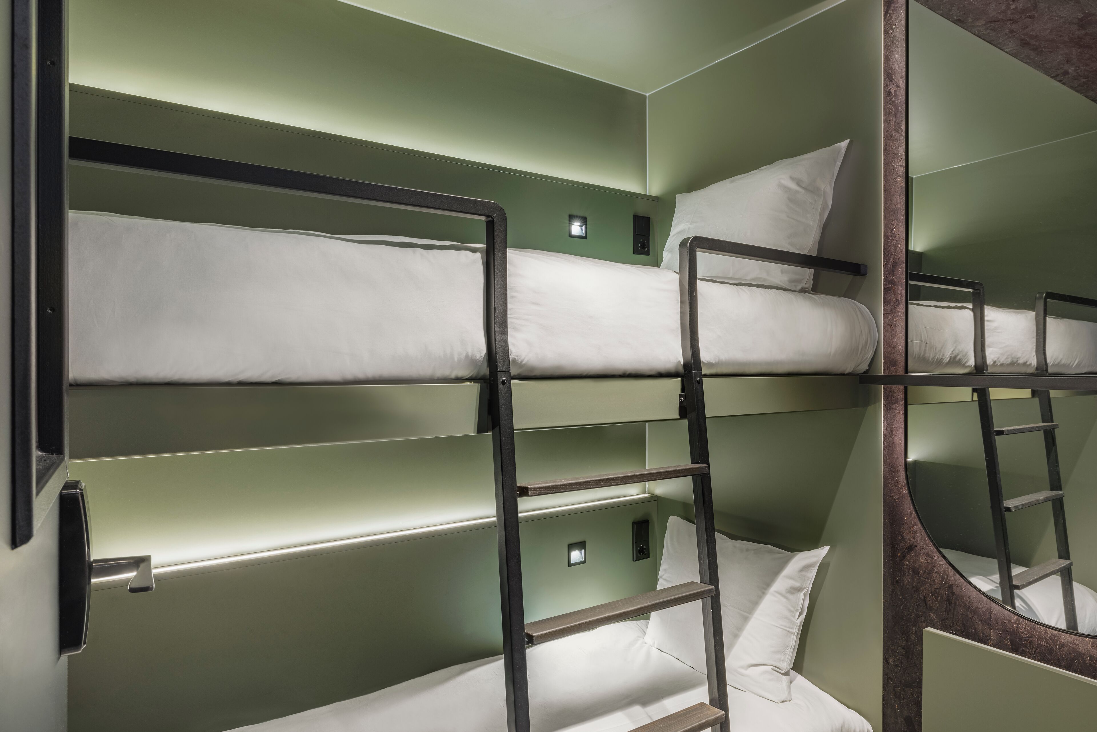 A bunk bed room with green walls and metal railings.