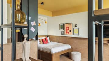 Un dormitorio moderno con una cama de madera, una mesita de noche pequeña, una lámpara colgante y una pared decorada con cuadros.