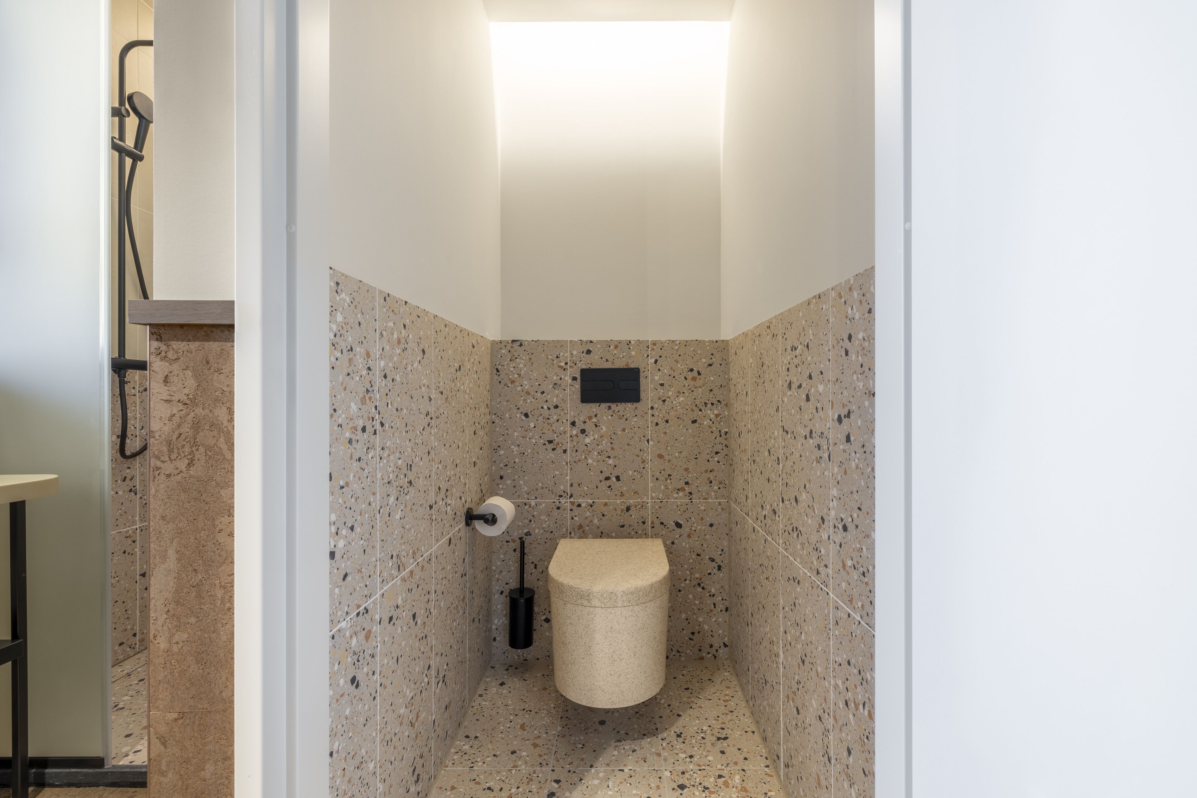 A small, modern bathroom with a toilet, a shower, and a towel rack.