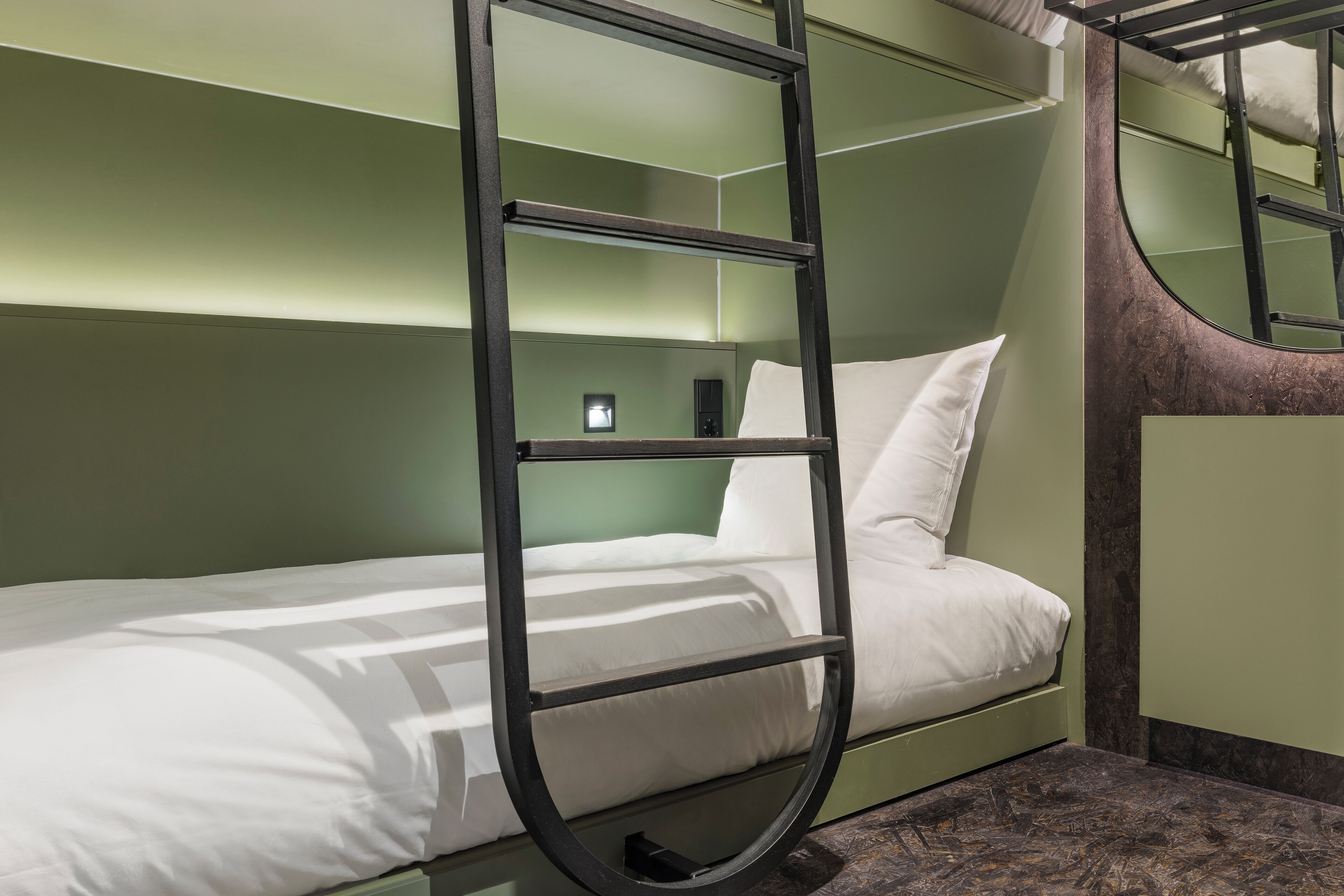 Una cama litera con escalera, una mesita de noche y un espejo.