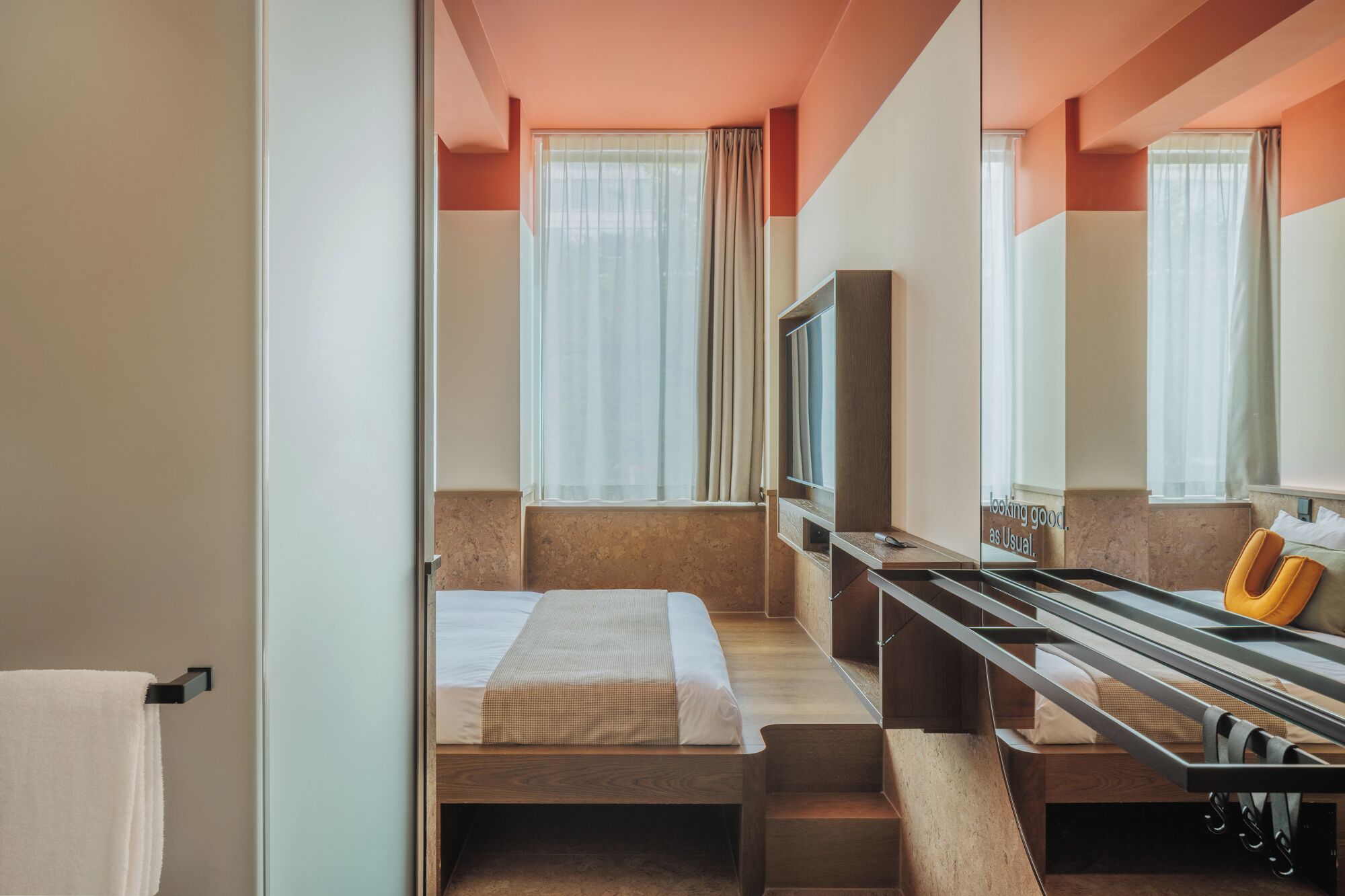 A hotel room with a bed, a TV, a desk, and a mirror.