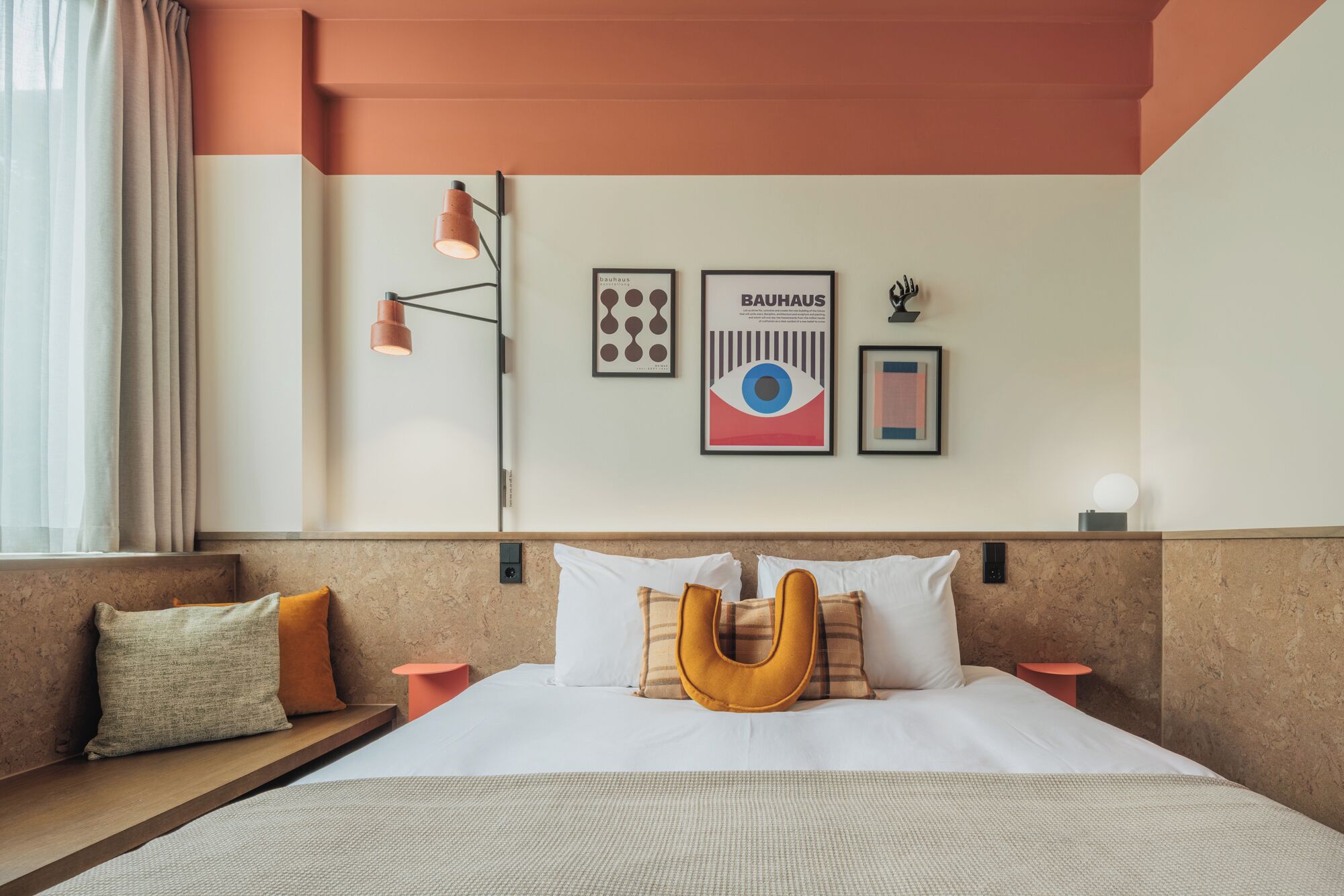 Habitación de hotel con una cama grande, cabecera de diseño único, mesita de noche y lámpara de pared.