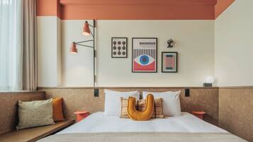 Habitación de hotel con una cama grande, cabecera de diseño único, mesita de noche y lámpara de pared.