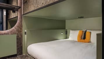 Habitación de hotel moderna con una pared curva, una cama con ropa blanca y una almohada naranja original.