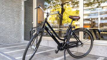 A stationary bicycle parked outside a building with a glass window reflecting the interior.