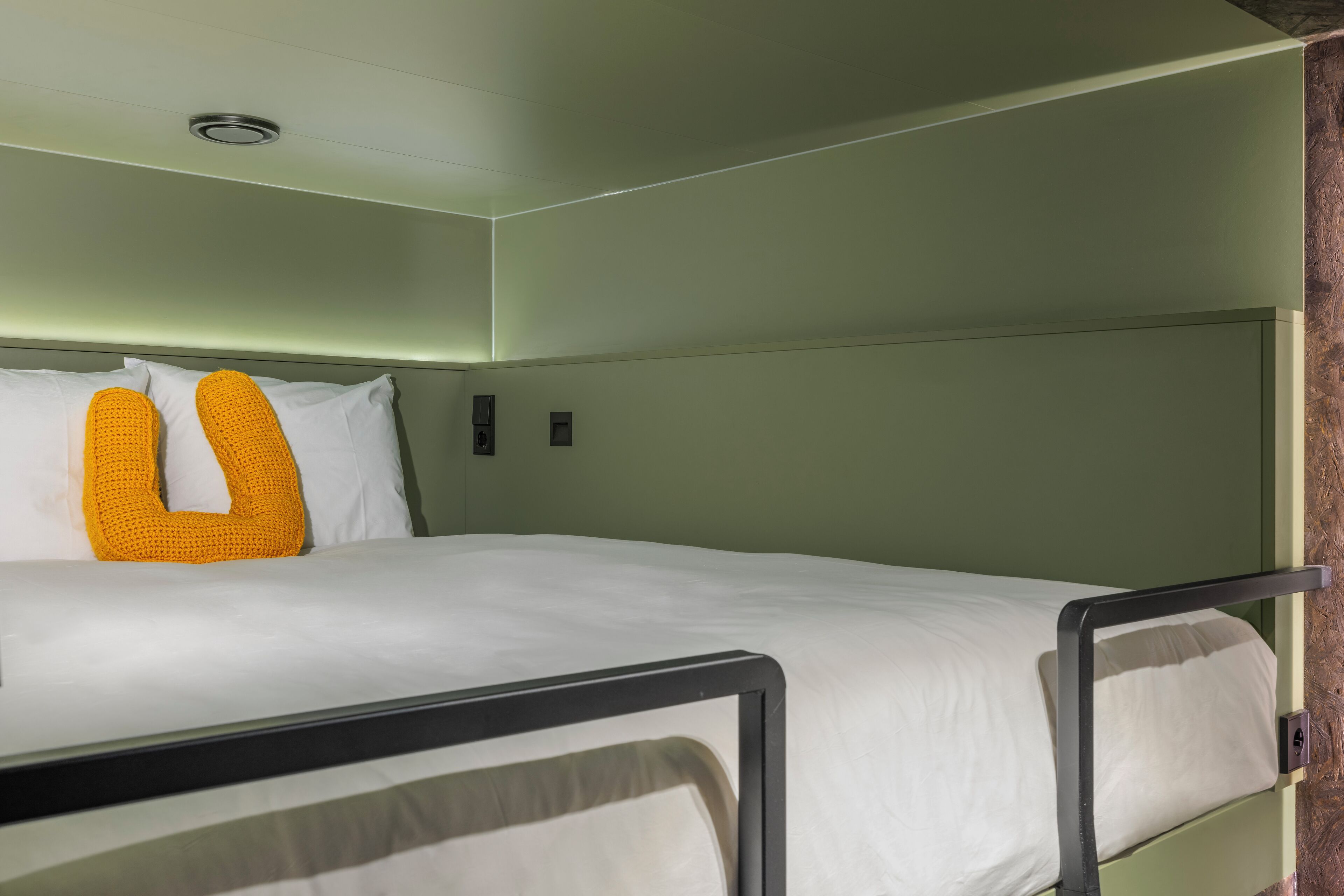 A bunk bed with a white mattress and a yellow pillow.