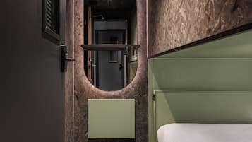 A modern bathroom with a marble wall, a green vanity, and a white bed.