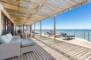 A deck with outdoor seating, a sofa, and a view of the sea. - Hangklip Villa (Pringle Bay)