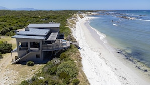 En fastighet vid stranden med ett modernt hus som har en balkong och en terrass.