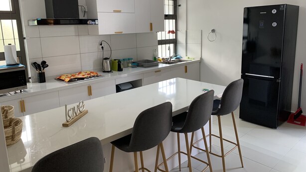 Una cocina moderna con armarios blancos, un refrigerador negro y una isla central con taburetes de bar.