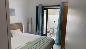 Un dormitorio con cama, una escalera de madera, una mesa y sillas fuera de la puerta.