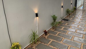 Un edificio moderno con fachada gris, un camino pavimentado y pequeñas plantas en el borde.