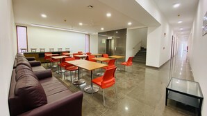 A modern dining area with high tables and chairs, a long bench, and a staircase leading to an upper level.