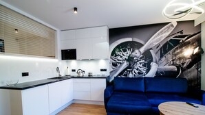A modern kitchen with white cabinets, a black countertop, and a large mural of a vintage airplane. - Apartament AVIATOR lokalizacja w centrum (Nowy Targ)