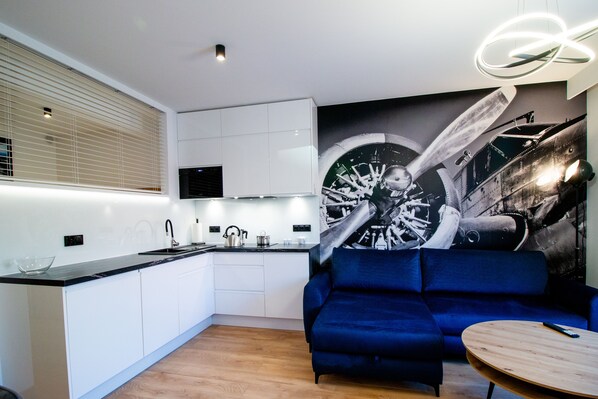 Una cocina moderna con armarios blancos, encimera negra y un gran mural de un avión antiguo.