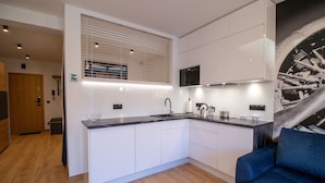 A modern kitchen with white cabinets, a black countertop, and a built-in stove. - Apartament AVIATOR lokalizacja w centrum (Nowy Targ)