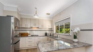 Une cuisine moderne avec des meubles blancs, un plan de travail en granit et un réfrigérateur en acier inoxydable.
