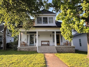 A two-story house with a porch, a front door, and a mailbox.