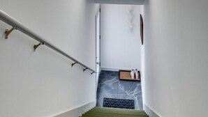 Eine Treppe mit Handlauf, einer Lampe am oberen Ende und einem kleinen Schuhregal.