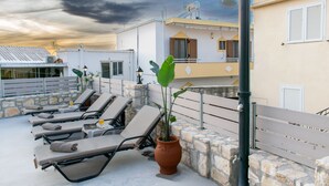 A rooftop with sun loungers, a potted plant, and a stone wall. - La Si'Ma, with private pool, 2-bedrooms close to Margarites Village (Plevriana)