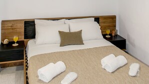 A bedroom with a wooden headboard, a bed with white linens, a brown throw blanket, and two rolled towels. There is a painting on the wall and a lamp hanging above the bed. - La Si'Ma, with private pool, 2-bedrooms close to Margarites Village (Plevriana)