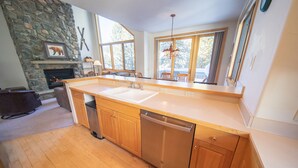 A modern kitchen with wooden cabinets, a dishwasher, and a stone fireplace. - Ironwood 2993 (Keystone)