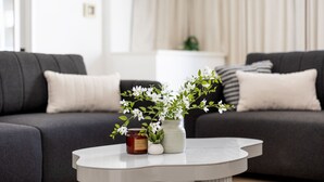 Ein modernes Wohnzimmer mit einem grauen Sofa, einem weißen Couchtisch und einer Vase mit weißen Blumen.