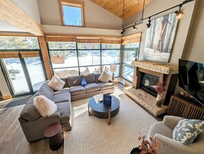 A modern living room with a fireplace, large windows, and a cozy seating area.