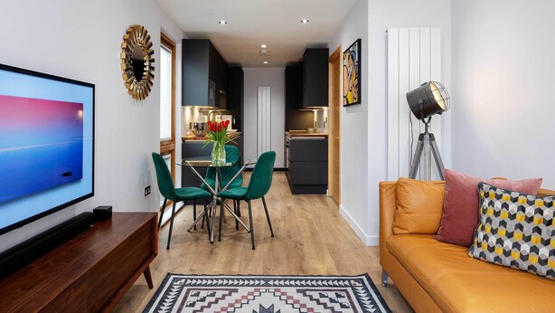 A modern living room with a TV, sofa, and dining area. - Old Town Chic, by Veeve (London)
