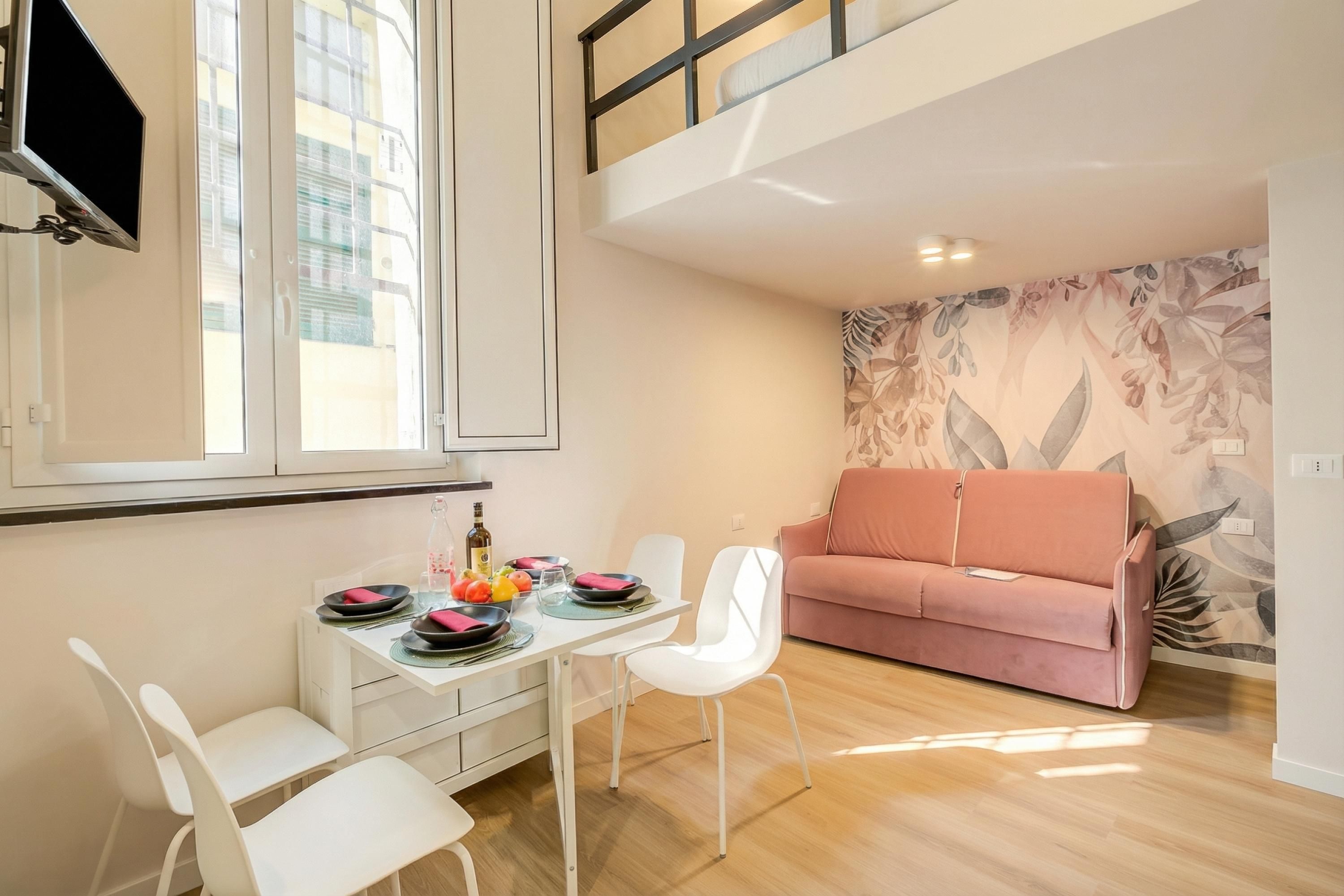A modern living space with a dining area, a pink sofa, and a large window.